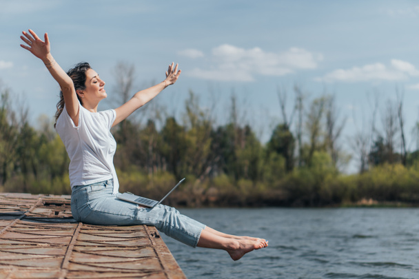 stock photo cheerful woman outstretched hands sitting lake